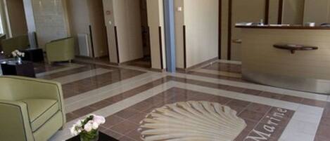 A lobby with a reception desk, a seating area, and a tiled floor with a marine-themed design.