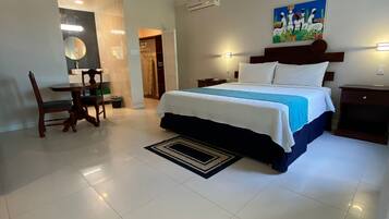 A bedroom with a bed, bedside tables, a desk with a chair, a mirror, and a painting on the wall.