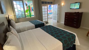 Une chambre d’hôtel avec deux lits, un ventilateur de plafond, une télévision et une vue sur l’extérieur.