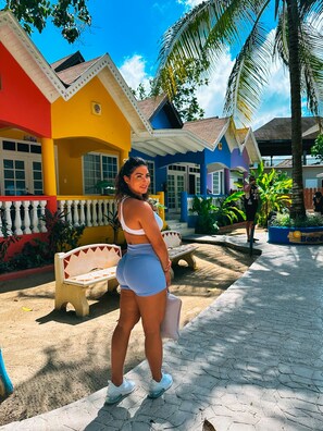 Un bâtiment aux couleurs vives, avec un banc et un palmier au premier plan.
