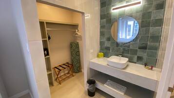 Un baño moderno con un lavamanos blanco, un espejo y una pared de azulejos verdes.