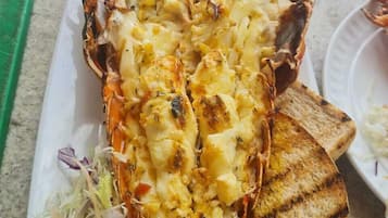 A lobster dish with grilled bread and a side salad on a white plate.