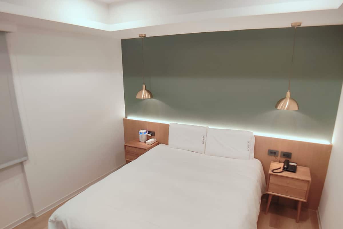 Ein modernes Schlafzimmer mit einem großen Bett, Nachttischen, einem Beistelltisch und einer Wandlampe.