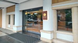 A hotel entrance with a glass door, a signboard, and a small outdoor seating area. - Fooyee Hotel Wenxinzq (Taichung)