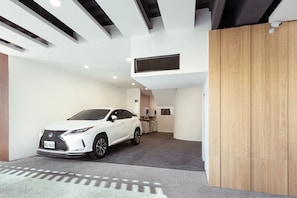Spacious room with high ceiling and exposed beams, featuring a wooden panel and carpeted floor.