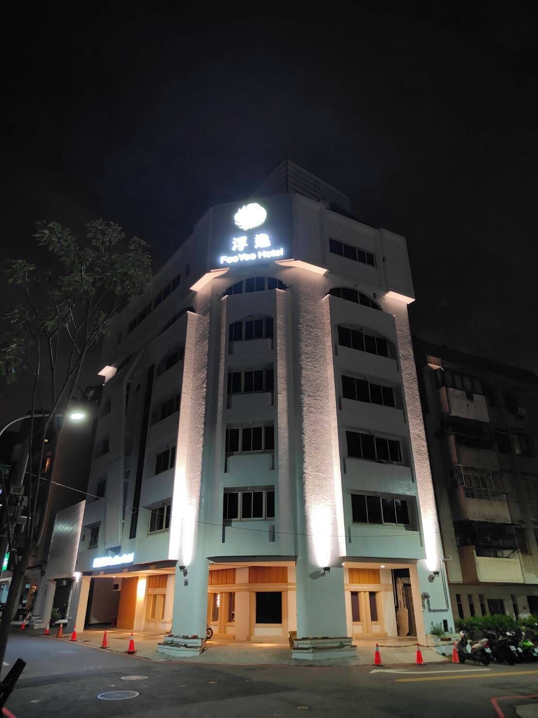 A hotel with a prominent sign at the top, multiple floors, and a well-lit entrance.