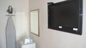 A bathroom with a mirror, a towel rack, and a small table with a bottle and a cup. - Searle Motel (Long Beach)