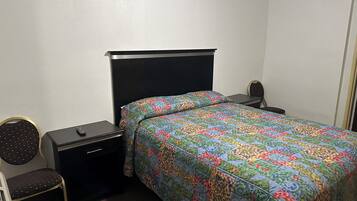 Una habitación de hotel con cama, mesita de noche, silla y escritorio.