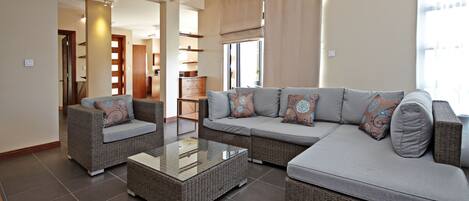 A living room with a sectional sofa, two armchairs, and a glass coffee table.