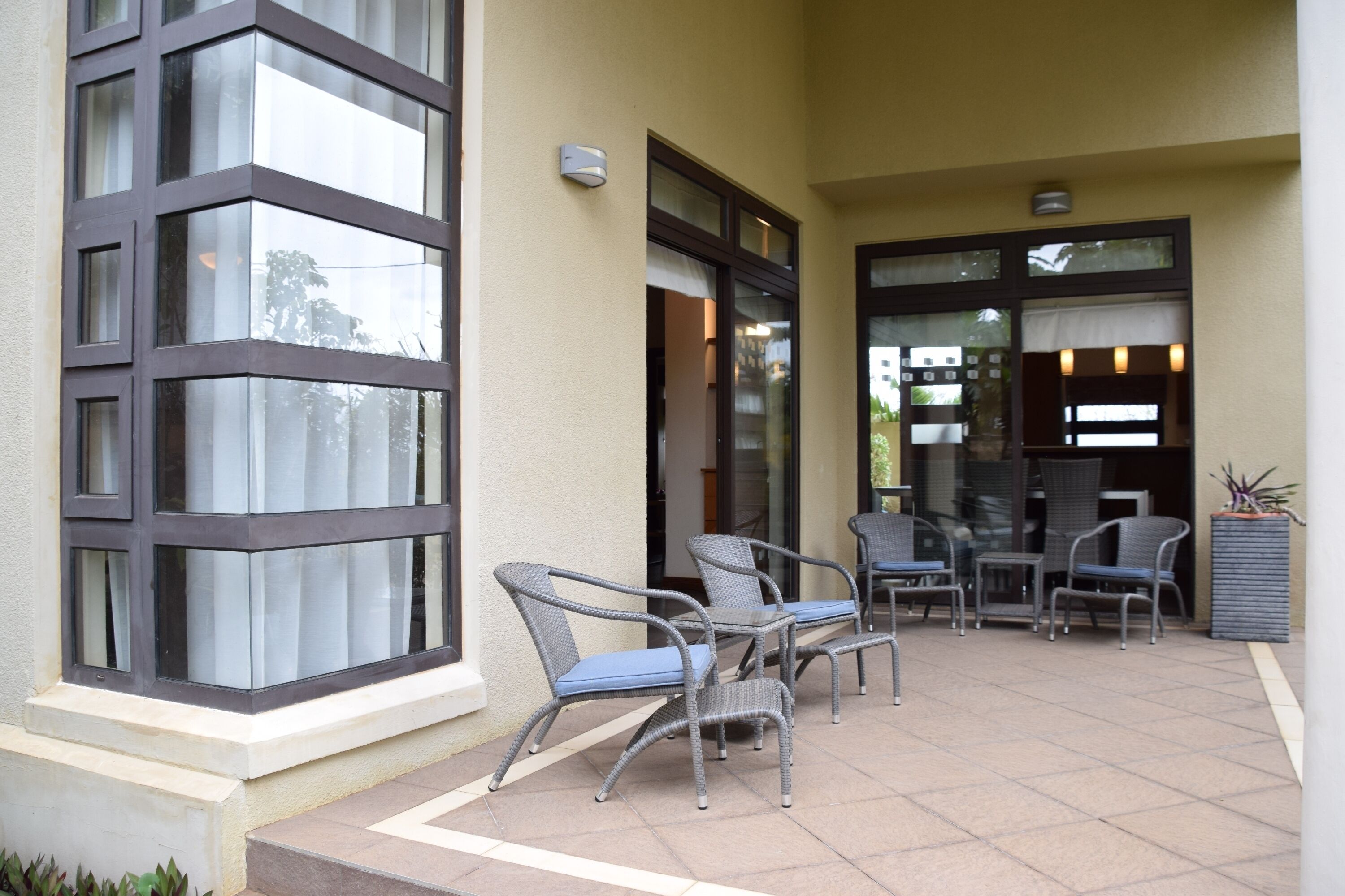 An outdoor patio area with wicker furniture and a glass door entrance.