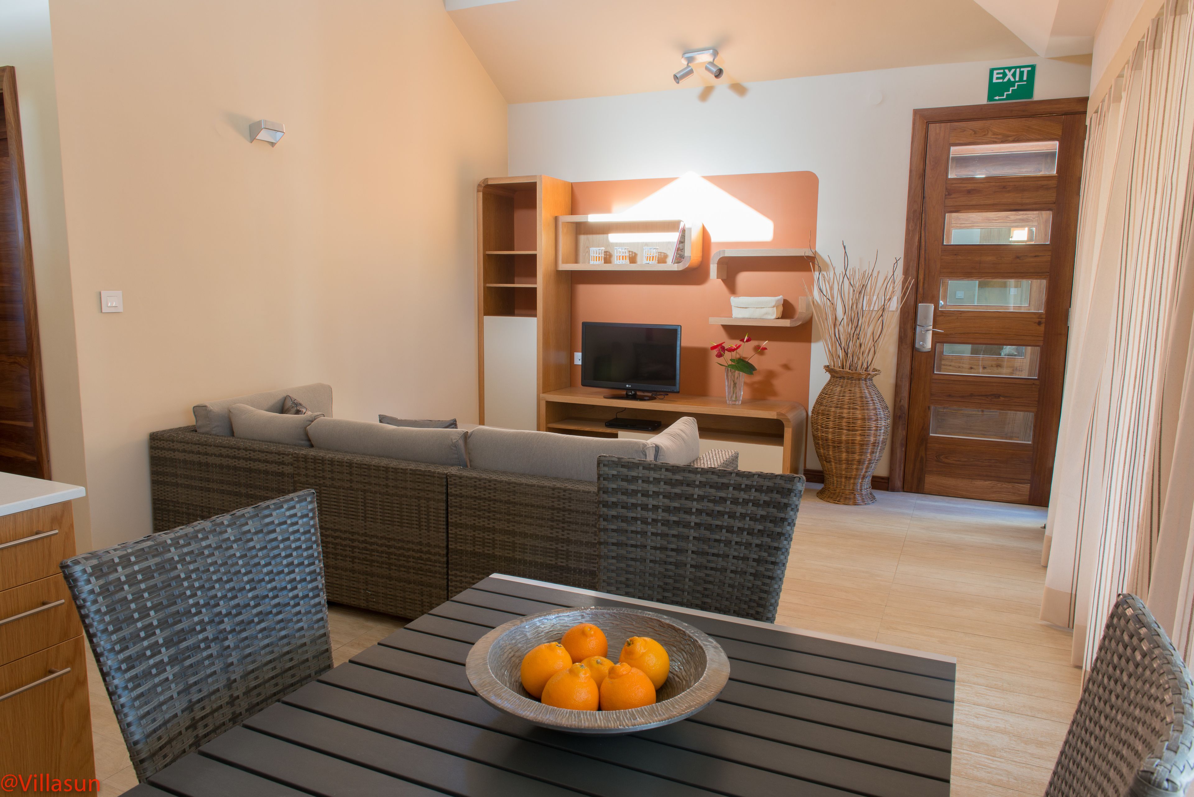 Un salón con un sofá, una mesa con un frutero y un televisor.