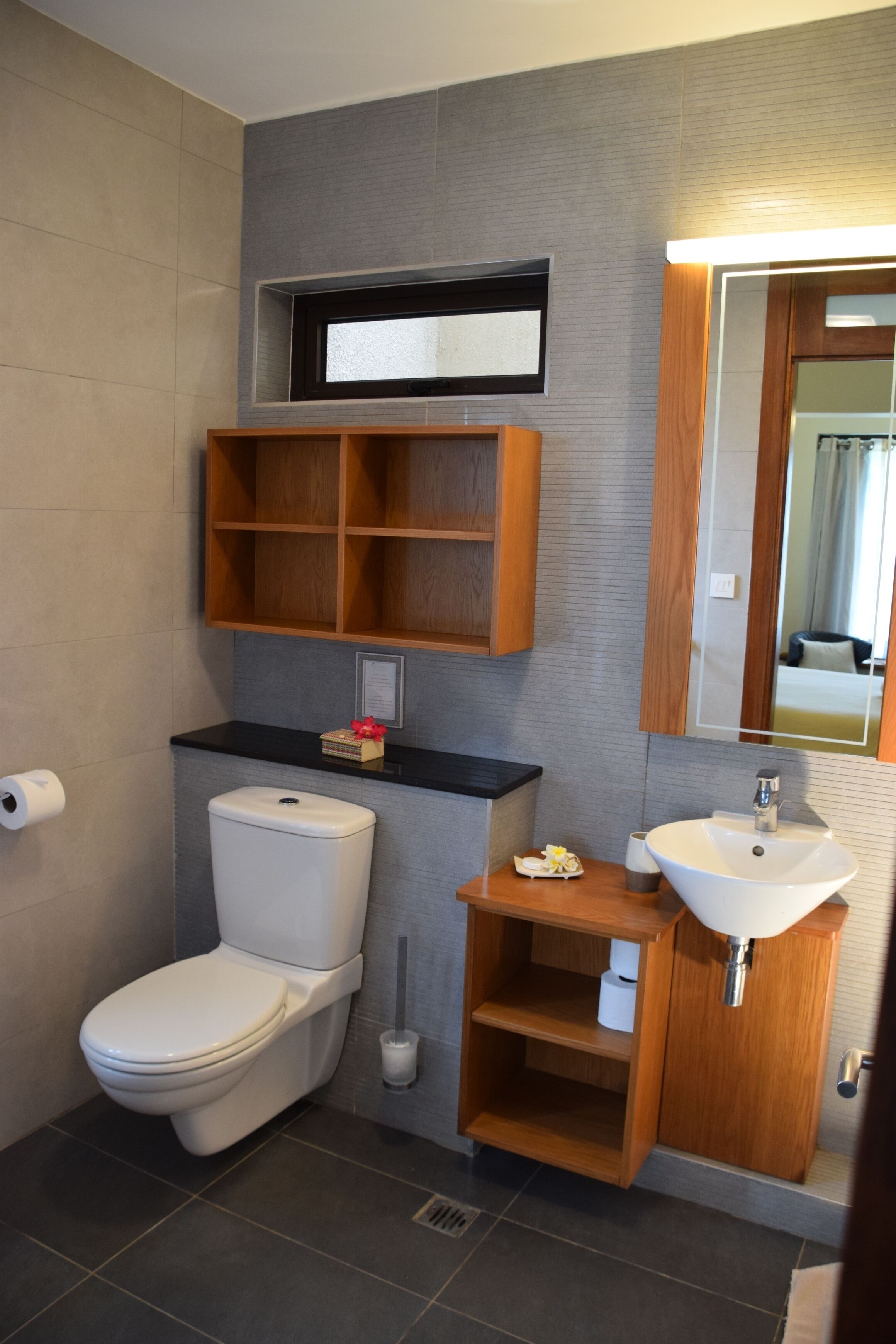 Un baño moderno con inodoro, lavamanos y estantes de madera.