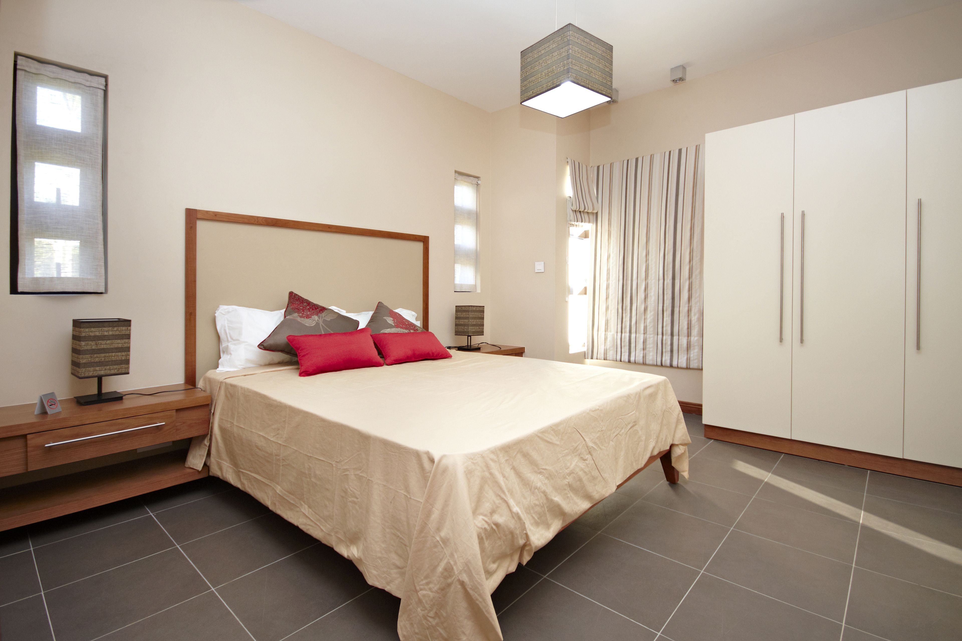 A bedroom with a large bed, bedside tables, a wardrobe, and a hanging light fixture.