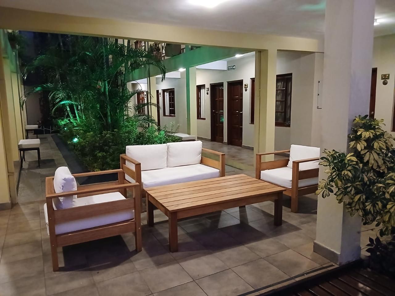 A hotel lobby with a wooden sofa set, a coffee table, and a potted plant.
