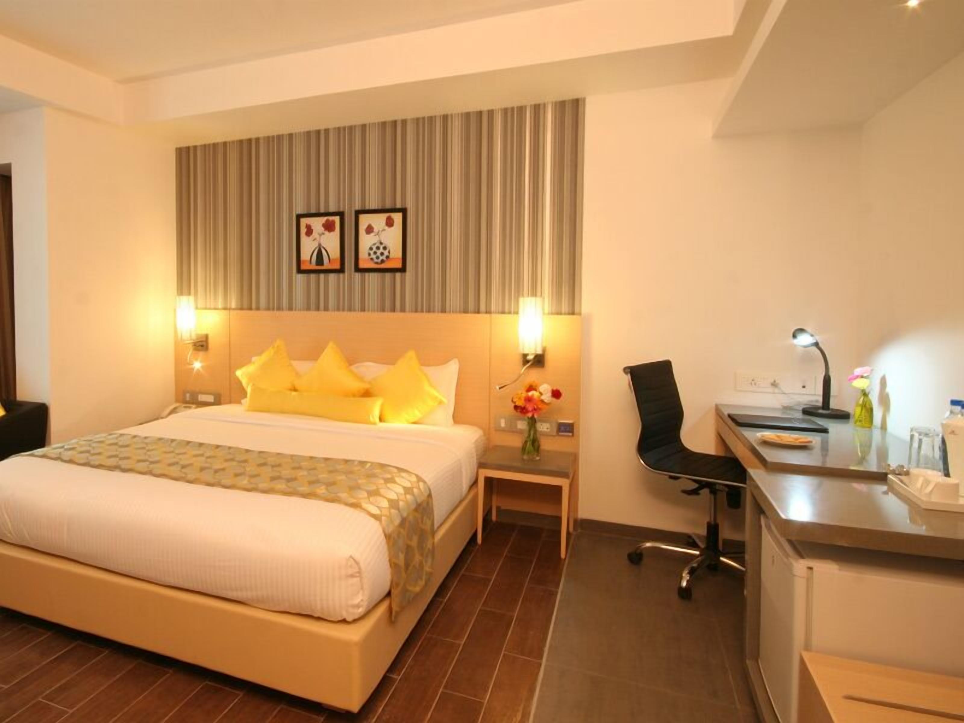 Una habitación de hotel con cama, mesitas de noche, escritorio y una silla.