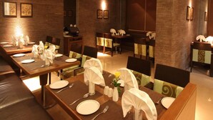 A dining area with multiple tables set for service, each with plates, cutlery, and napkins. - Landmark Residency (Mumbai)