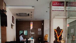 A reception area with a receptionist, a desk, a computer, a statue, and a signboard. - Landmark Residency (Mumbai)