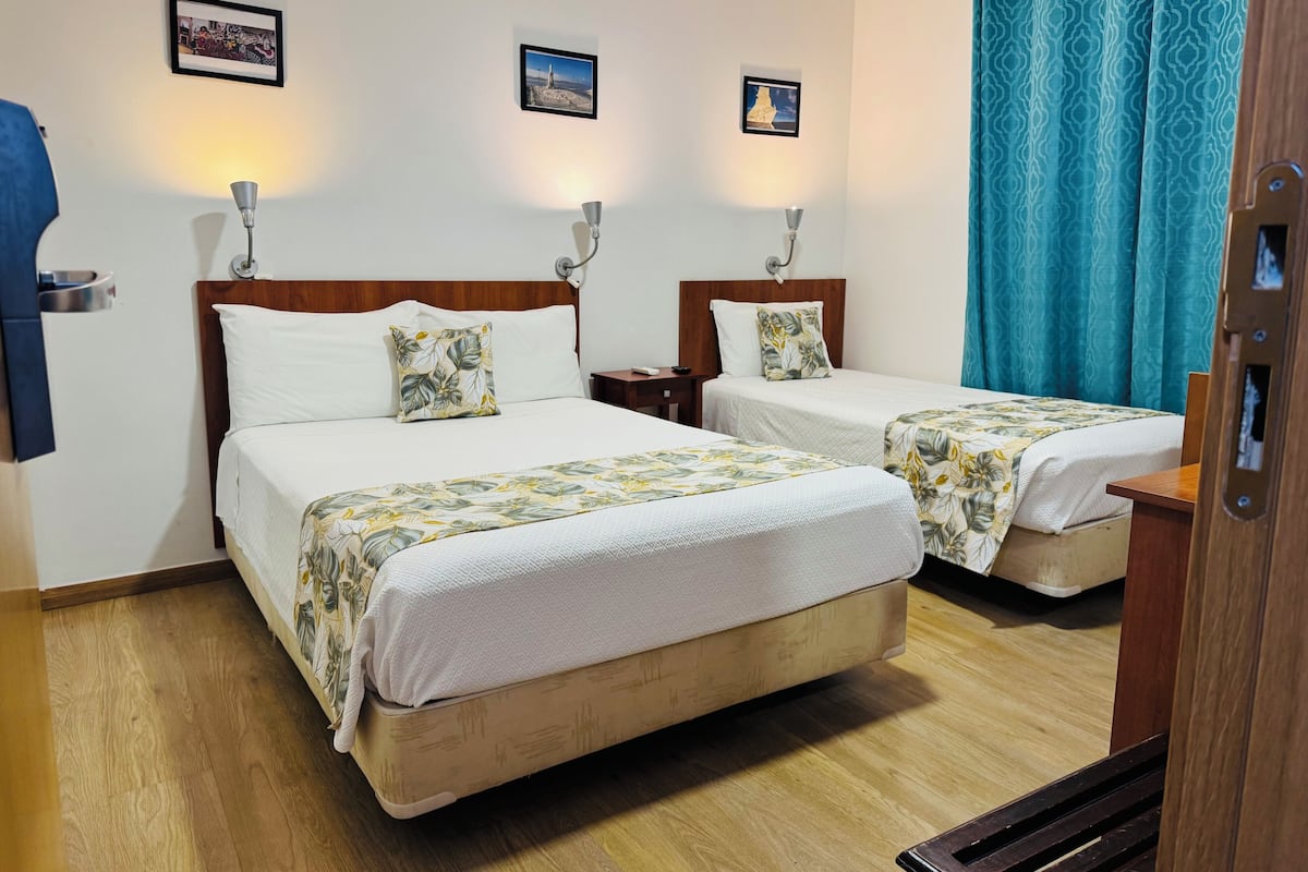 A hotel room with two beds, wooden headboards, and a wooden floor.