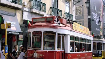 A red and white tram on a cobblestone street with passengers.