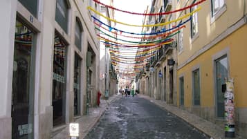Uma rua estreita ladeada por edifícios, decorada com guirlandas coloridas.