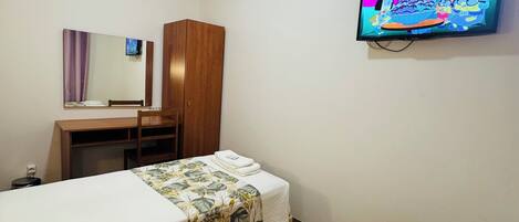 Una habitación de hotel con dos camas, un armario de madera, un escritorio con silla, un televisor y un espejo.