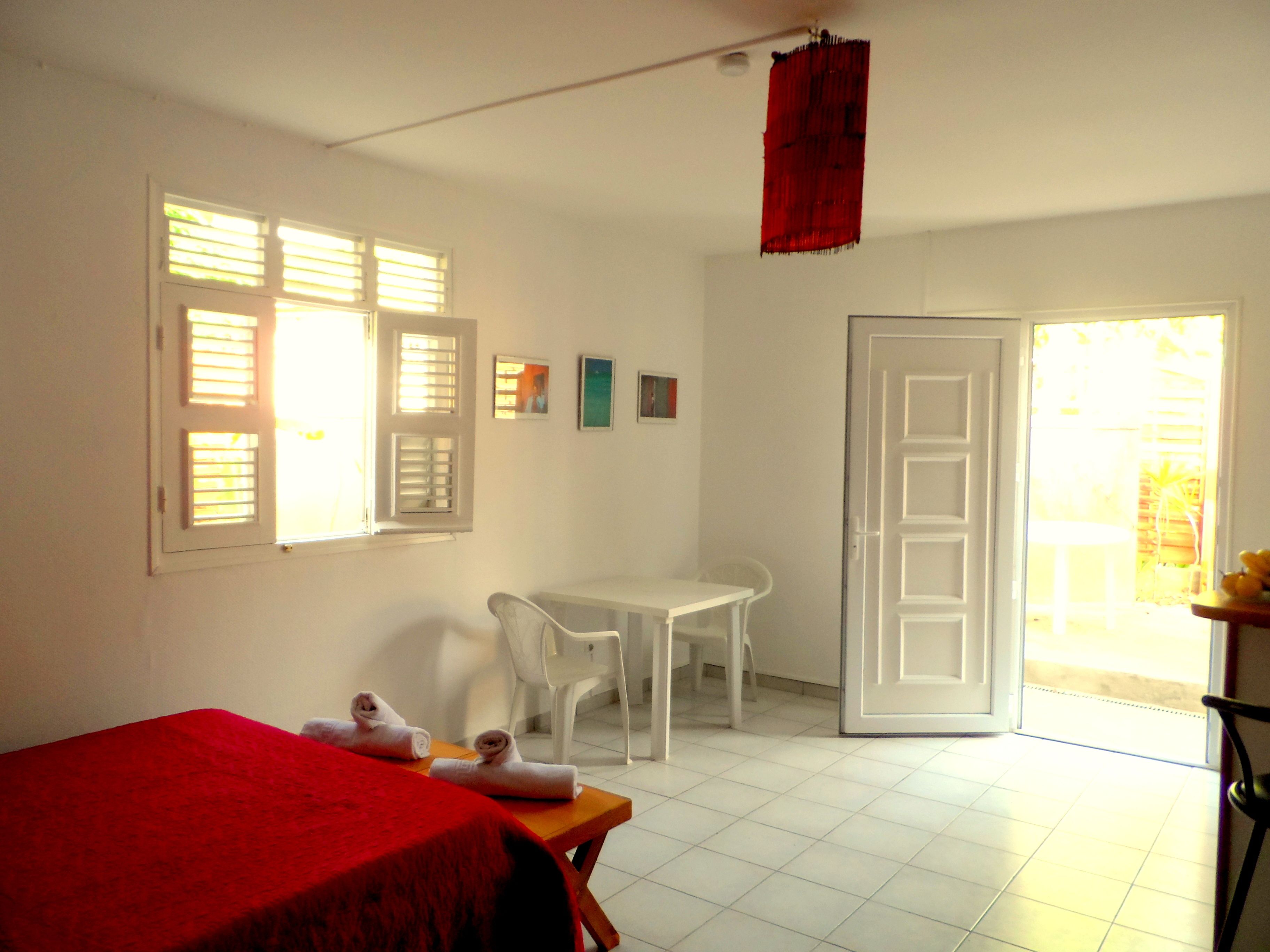 Una habitación con cama, una mesa, una silla y una puerta que da a un área exterior.