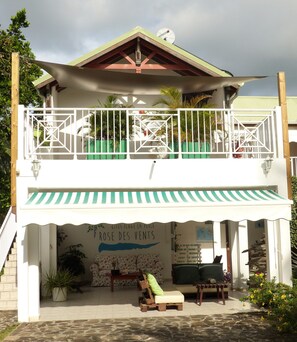 A two-story building with a balcony, a covered patio area, and a sign that reads "Gites plage la perle". - Rose des Vents (Deshaies)