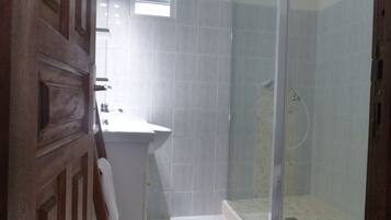 Une salle de bain avec une douche, un lavabo et une porte en bois.