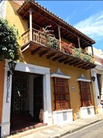 Un edificio amarillo con un balcón decorado con flores, un letrero que dice 
