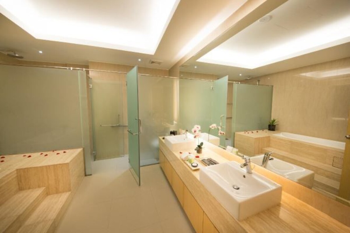 Un baño moderno con un espejo grande, dos lavamanos y un box de ducha de vidrio.