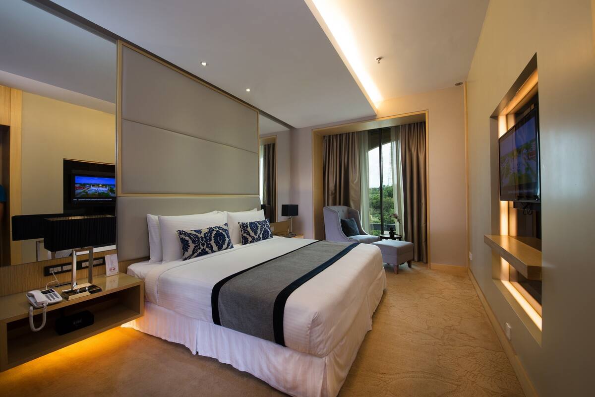 A modern hotel room with a large bed, a flat-screen TV, a desk with a phone, and a chair.
