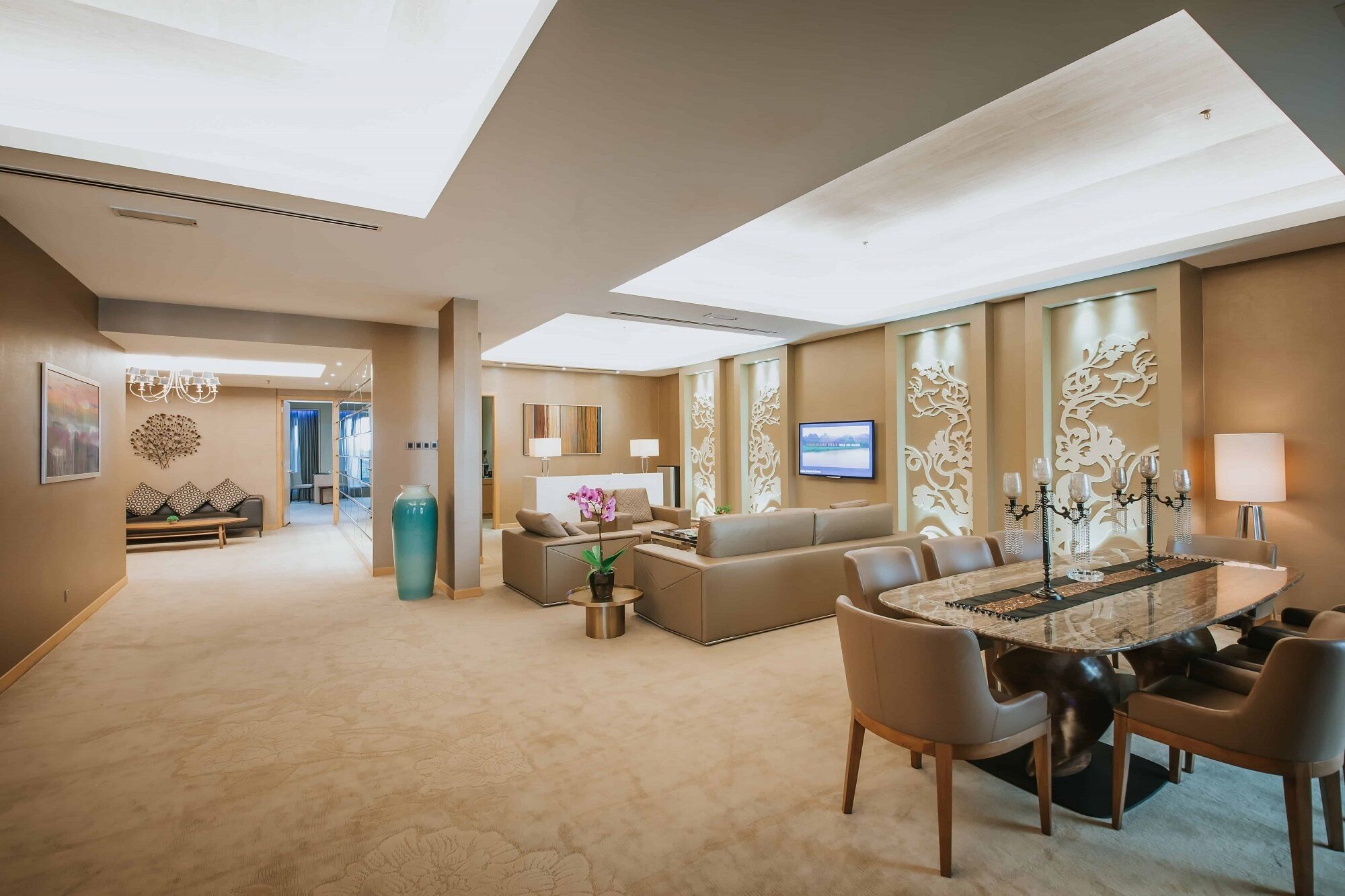 A spacious hotel lobby with a reception desk, seating area, and a dining table with chairs.