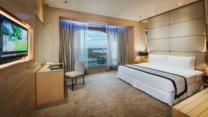 A hotel room with a large bed, a desk with a chair, a television, and a view of the outdoors. - Ancasa Royale Pekan Pahang (Pekan)