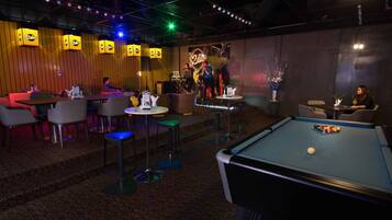 A billiards table, bar seating, and a stage with performers.