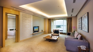 A modern hotel room with a living area featuring a sofa, a coffee table, a TV, and a view of the outdoors. - Ancasa Royale Pekan Pahang (Pekan)