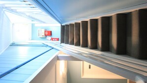 A corridor with a skylight, a ventilation system, and a red emergency exit sign. - The Cliff House (Kangaroo Point)