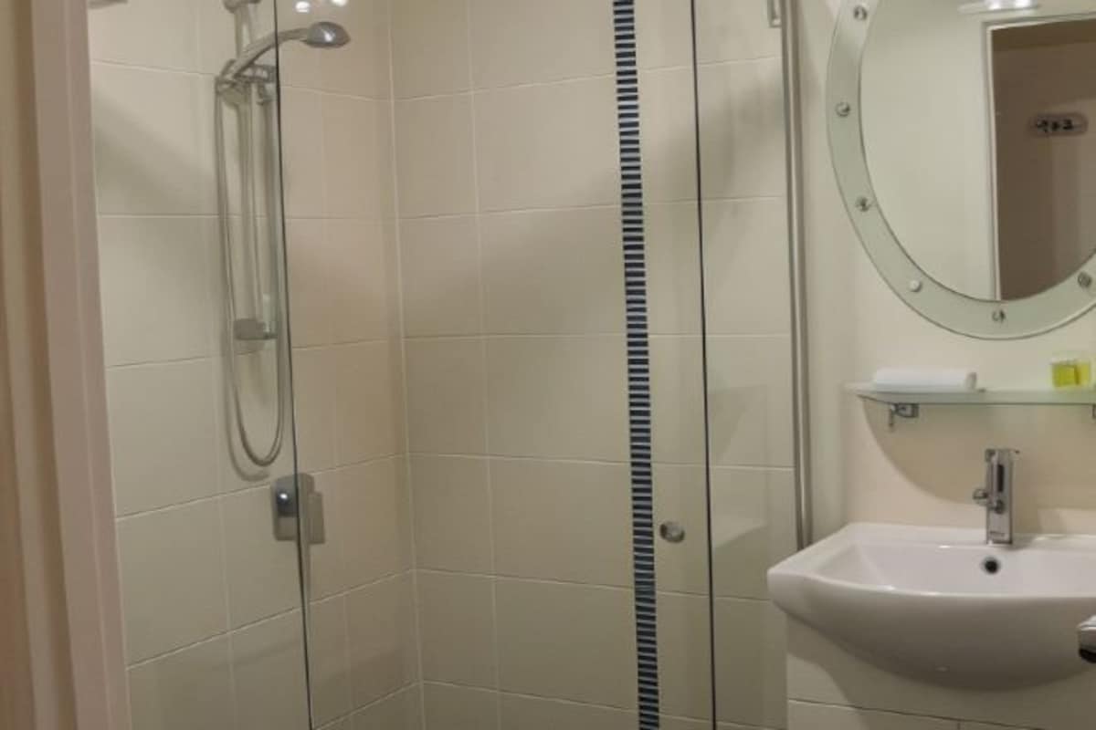 Une salle de bain avec une douche à parois de verre, un lavabo avec un miroir et des toilettes.