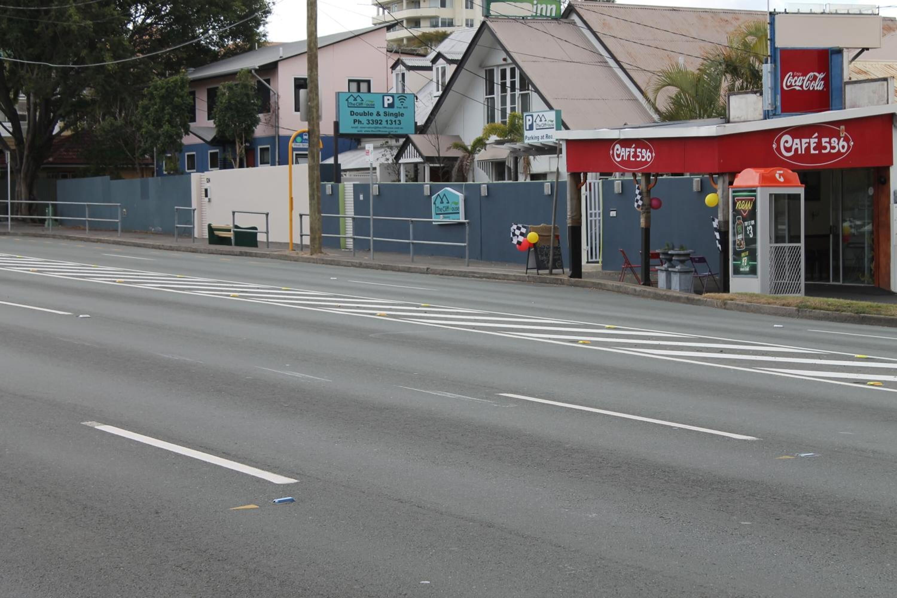 A street view with a café named Café 536, a parking sign, and a building with a Coca-Cola sign.