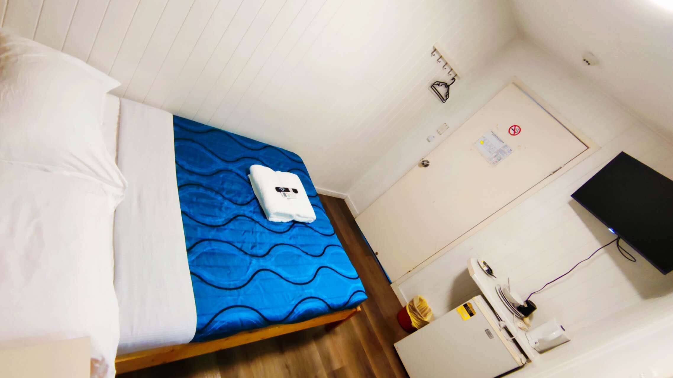 Habitación de hotel con cama, escritorio, silla, televisor y puerta.