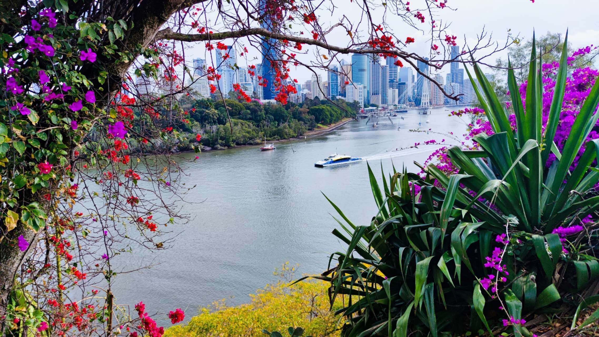 Un río con barcos, rodeado de exuberante vegetación y flores coloridas.