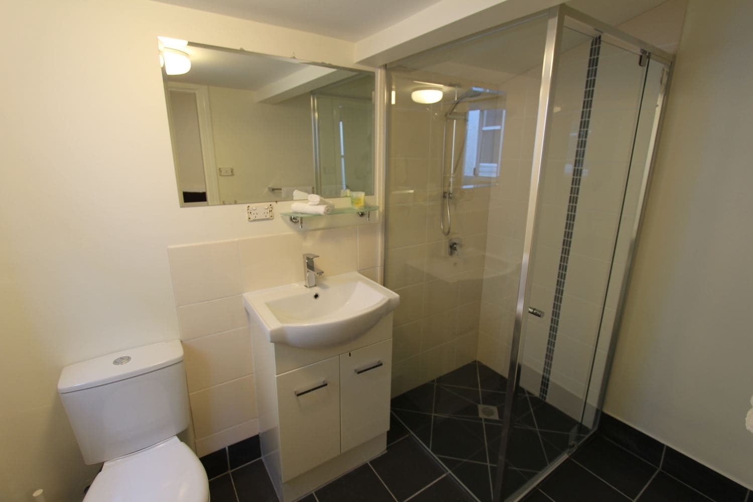 A bathroom with a toilet, sink, and shower.