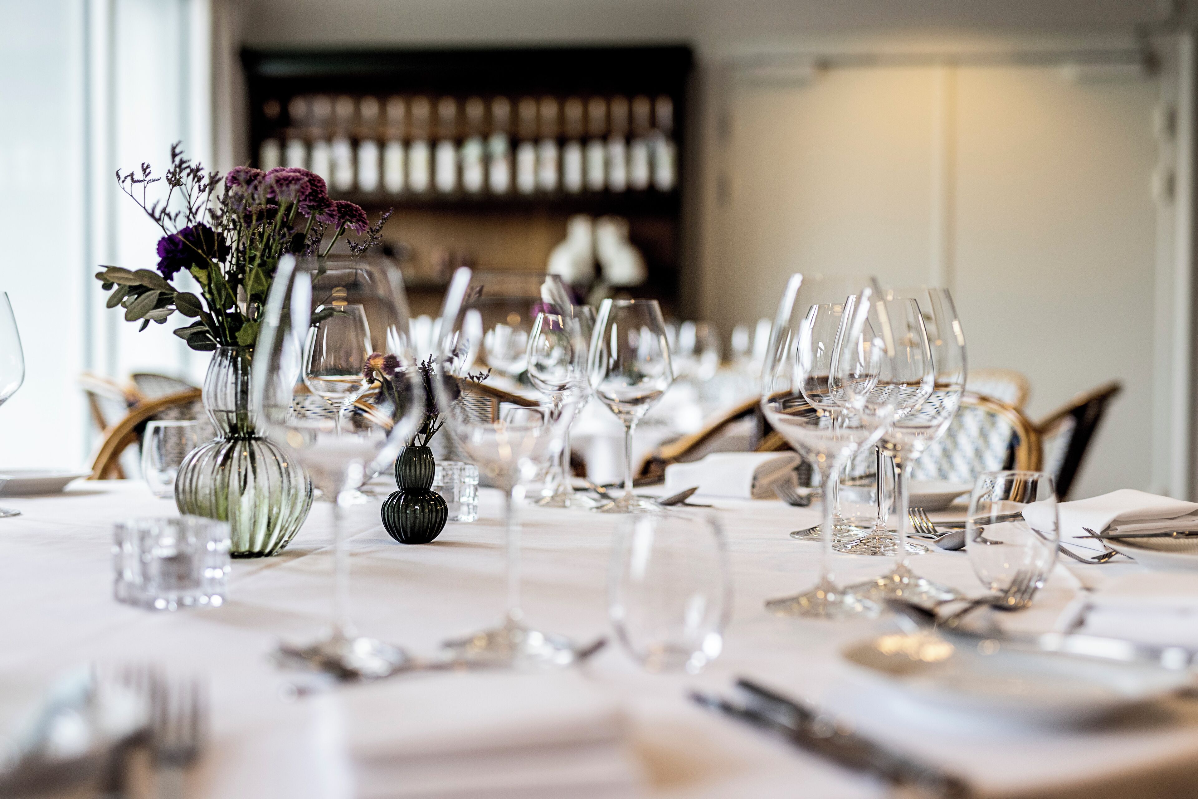 A table set for a formal dining experience with multiple wine glasses, water glasses, and cutlery.
