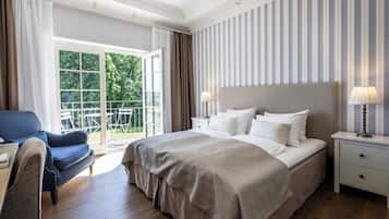 Habitación de hotel con una cama grande, una silla, una mesita de noche y vistas al exterior.