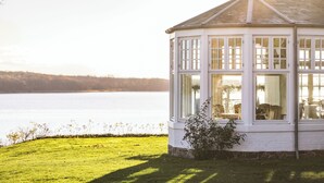 A white building with large windows overlooking a lake. - Stella Maris (Svendborg)