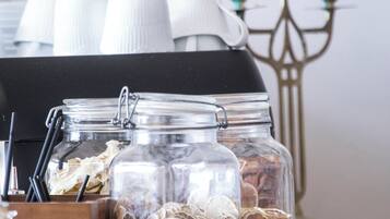 Uma mesa com potes de vidro contendo fatias de cítricos secos, um castiçal com velas acesas e uma cafeteira.