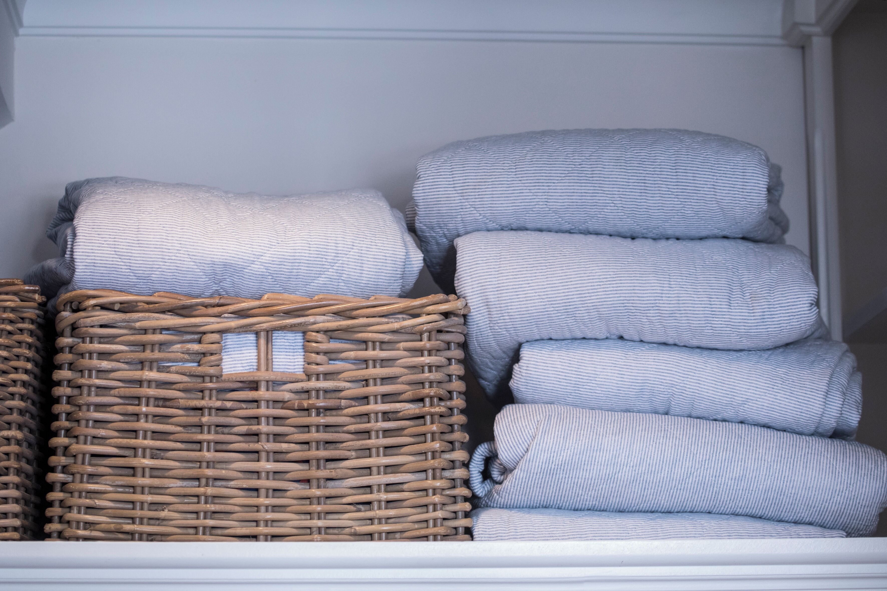 A storage area with wicker baskets and stacked pillows.