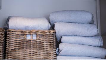 A storage area with wicker baskets and stacked pillows.