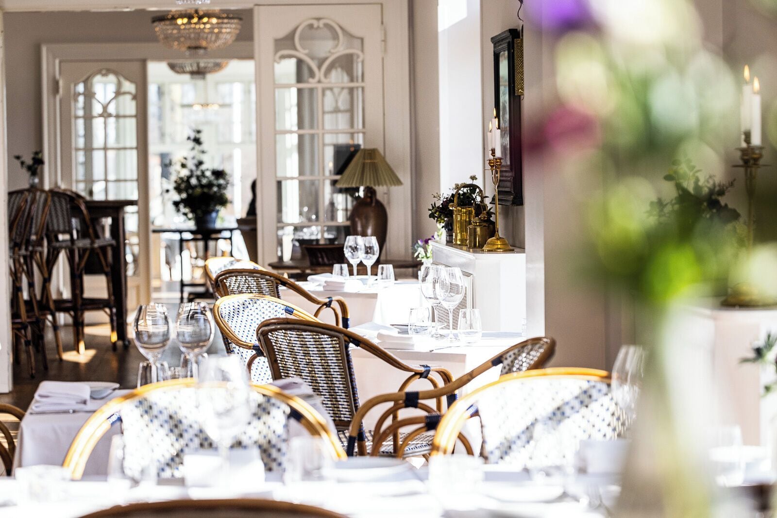 A dining area with wicker chairs and white table settings, including wine glasses and plates.