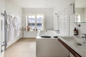 Un baño moderno con bañera, un espejo grande y una ventana con vistas al exterior.