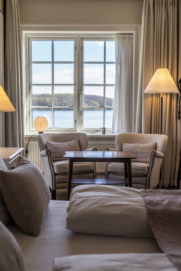 Una habitación de hotel con un ventanal grande, un sofá, una mesa y dos lámparas.